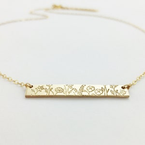 Gold-tone bar necklace with engraved floral pattern pendant on a fine chain