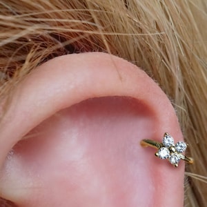 Sterling silver flower CZ huggie hoop earring on ear, small cartilage hoop