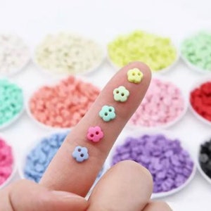 Small resin mini flower button in pastel colors, held in a hand