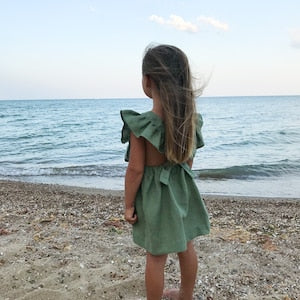 Sage green baby pinafore dress with ruffled shoulders and short gathered skirt