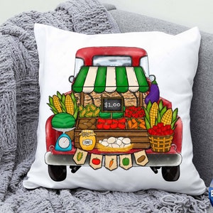 White throw pillow with red farm truck graphic and vegetable produce stand illustration