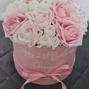 Pink flower hat box with mixed roses, satin ribbon bow, and a banner card with birthday text