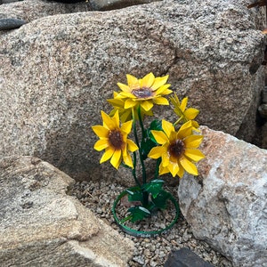 Small metal sunflower bouquet yard art with yellow petals, purple centers, and green leaves