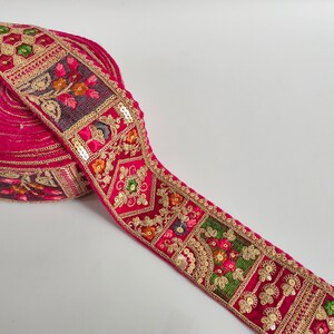 Embroidered floral border trim with gold sequins, on magenta lace fabric