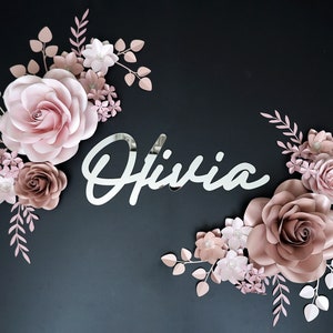 Pink and blush paper flower wall decor with leaf accents and cursive Olivia sign