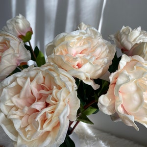 Artificial peony centerpiece with large cream and pale peach blooms and green leaves