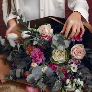 Fresh flower bouquet with pink and white roses, magenta blooms, eucalyptus leaves, dark ribbon