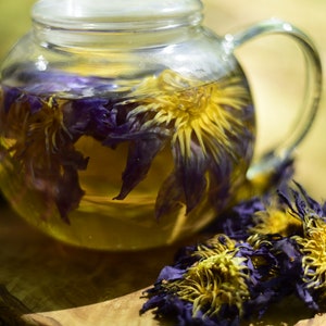 Glass jar of blue lotus resin & extract powder with purple and yellow flowers