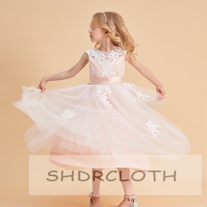 Blush flower girl dress with lace bodice, illusion neckline, and layered tulle skirt