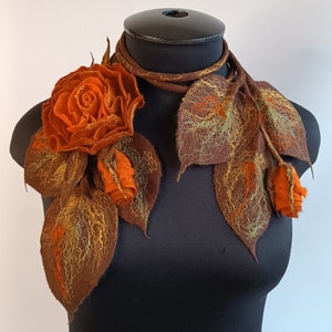 Orange felt flower brooch bouquet with leaf-shaped accents on scarf lariat