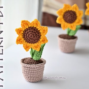 Crocheted mini sunflower in small pot, orange petals with brown center and green leaves