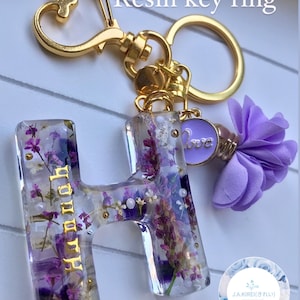 Gold-tone resin letter H key ring with dried purple flowers and round clasp