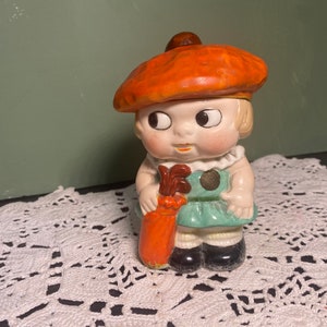 Vintage golfer girl figurine with googly eyes, orange hat, and golf club