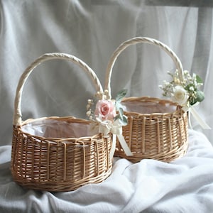 Wicker flower girl baskets with curved handles, ribbon trim, and small white blooms