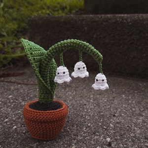 Crochet ghost flower decoration in a pot with green leaves and three small white ghosts
