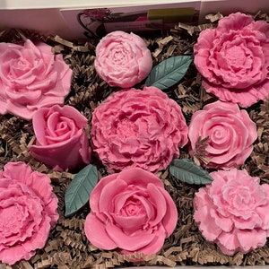 Pink rose-shaped soap flowers in a flower box, with green leaves