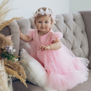 Pink tulle tutu dress with bow details and layered skirt, worn with matching headband