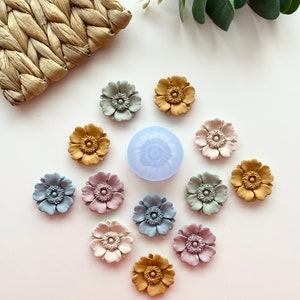 Blue silicone flower mold with raised rose blossoms and small clay flower pieces
