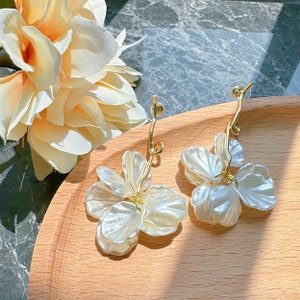 Gold drop earrings with white shell-flower petal blossoms and dangling hoops