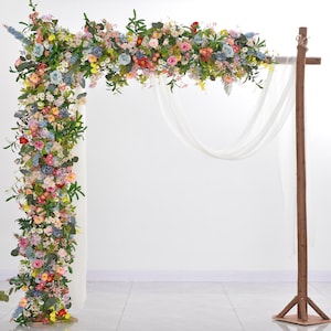 Wedding floral arch arrangement with pastel blooms and white draped fabric