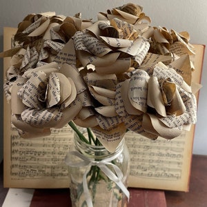 Book page rose bouquet in clear glass vase with tied stems, beige paper petals