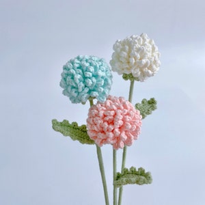Crochet flower bouquet with three pastel blooms and green leaves on stems