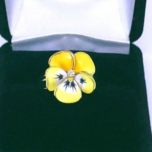 Yellow enamel flower ring with small clear center gemstone and blue accents