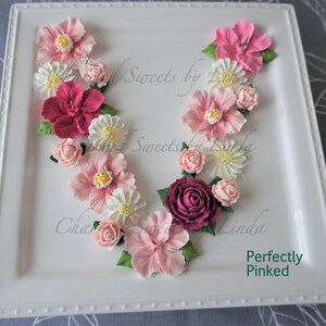 Pink and rose icing flowers arranged in a letter wreath for cake decorating