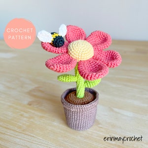 Pink crochet flower with yellow center, green stem, in knitted fabric pot