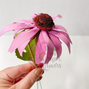 Mini pink coneflower paper flower with dark center, held by hand on a stem