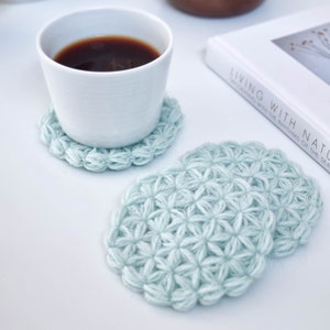 Crochet flower coaster in light blue, scalloped edge, round textured pattern