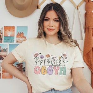 Cream T-shirt with floral line art and pink "OBGYN" print