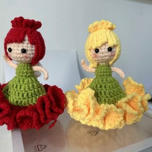 Two handmade crocheted fairy dolls, one red and green, one yellow and green, flower hair.
