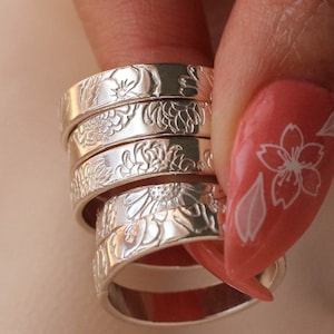 Stacked sterling silver rings with engraved floral birth-flower motifs