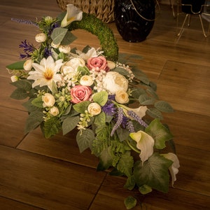 Artificial memorial grave flower arrangement with pink, cream, and purple blooms and leaves