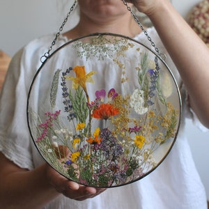 Circular pressed flower glass frame with real wildflowers under glass