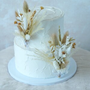 White wedding cake with dried flower cake topper arrangement