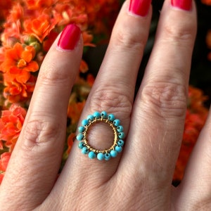Turquoise flower ring with stainless steel band and circular center, worn on hand