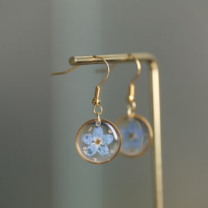 Gold forget-me-not flower resin drop earrings with blue circular dangles and tiny white blossoms
