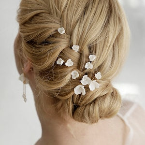 Set of 8 bridal hair pins with white floral pieces on a blonde updo