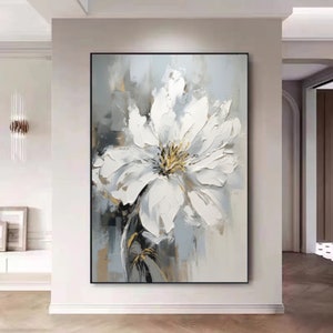 Framed canvas floral wall art with large white blossom and gold center on gray background