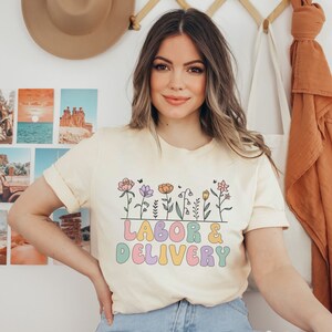 Cream T-shirt with colorful floral “LABOR DELIVERY” graphic, short sleeves