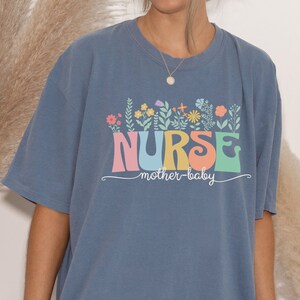 Blue crewneck short-sleeve T-shirt with colorful 'NURSES' floral front graphic