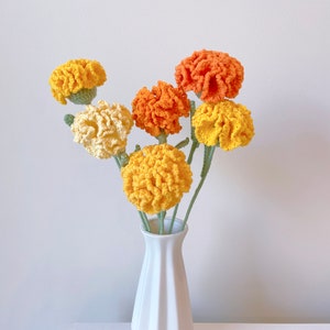 Crochet flower bouquet with orange and yellow blooms in clear glass vase