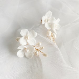 White floral wedding earrings with pearl accents and gold-tone stems