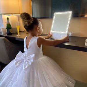 White sleeveless tulle dress with bow at the back and knee-length skirt