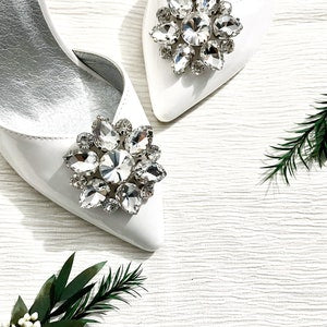 Sparkling rhinestone flower shoe clips with crystal centers on silver dress shoes