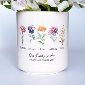 White personalized flower pot with colorful birth flowers, names, and Our Family Garden text