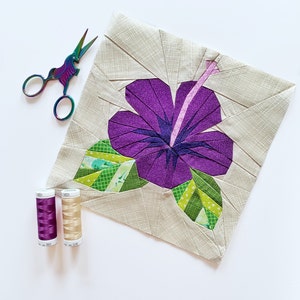 Hibiscus flower quilt block pattern with purple and green petals on fabric template