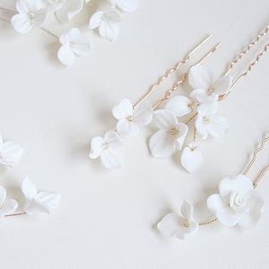White porcelain flower hairpins with delicate blossoms on thin gold-tone stems